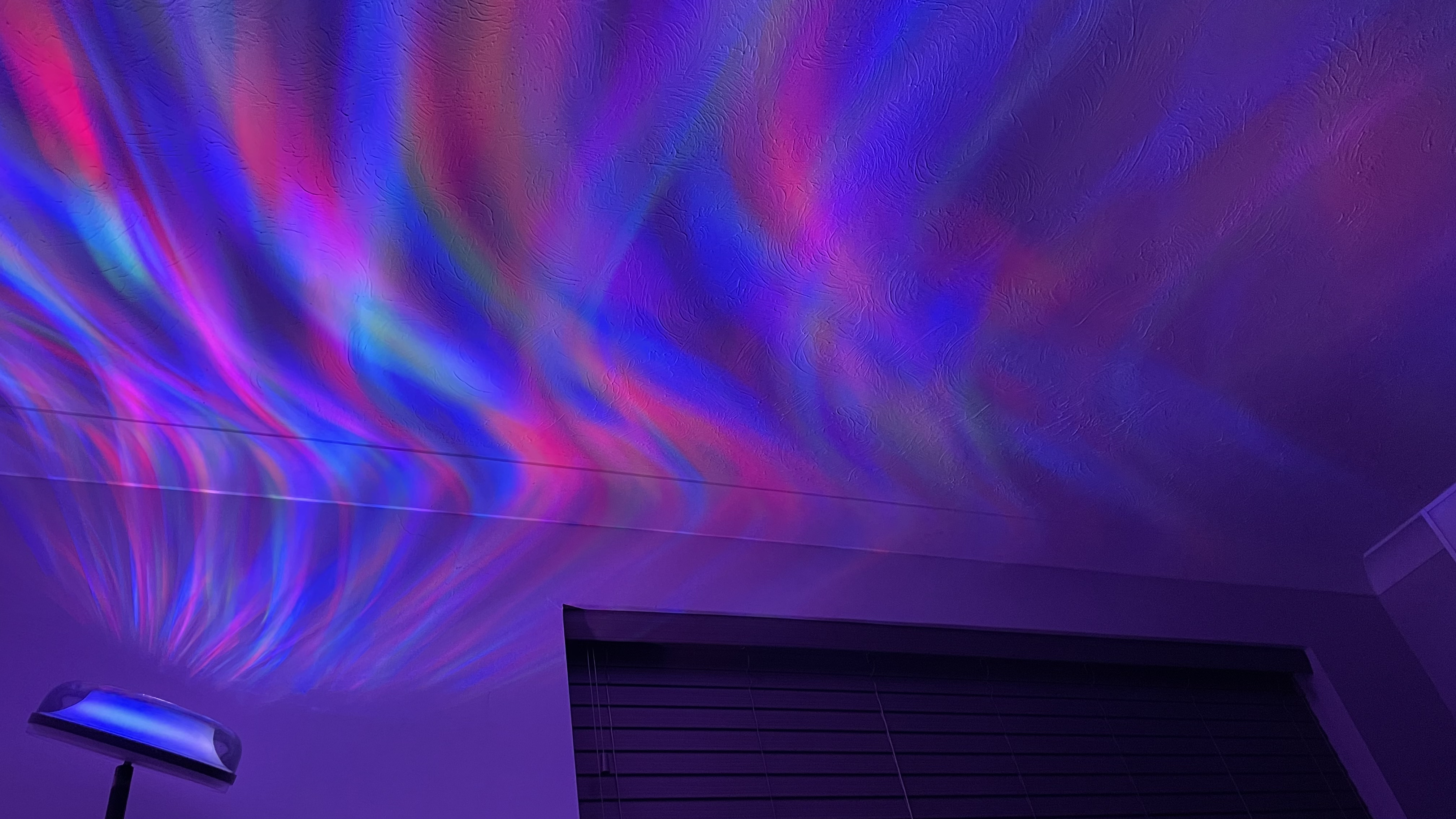 The Govee Uplighter Floor Lamp is projecting an aurora borealis effect onto a bedroom ceiling.