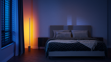 Philips Hue Gradient Signe Floor Lamp in use in a bedroom next to a bed