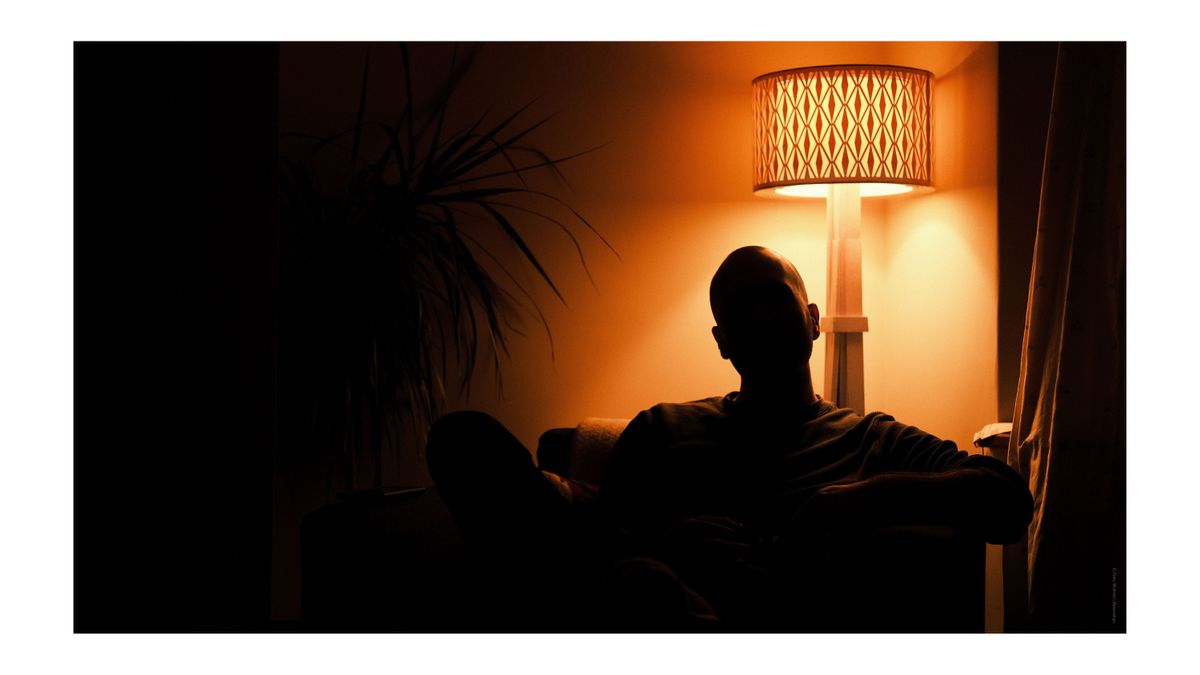 A photo of a man silhouetted against an orange light source