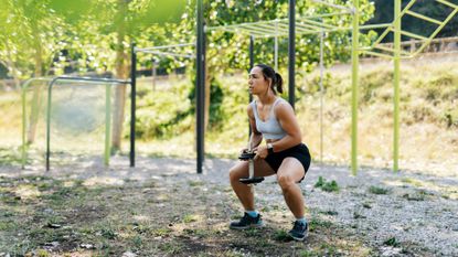 A woman performing a dumbbell squat