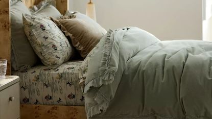 Layered bedscape featuring a burl wood frame, floral sheets, and a moss green ruffle velvet duvet