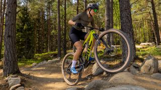 A women rides up a rock step with the new ohlins suspension