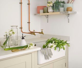 butler sink with exposed copper pipes running to copper taps