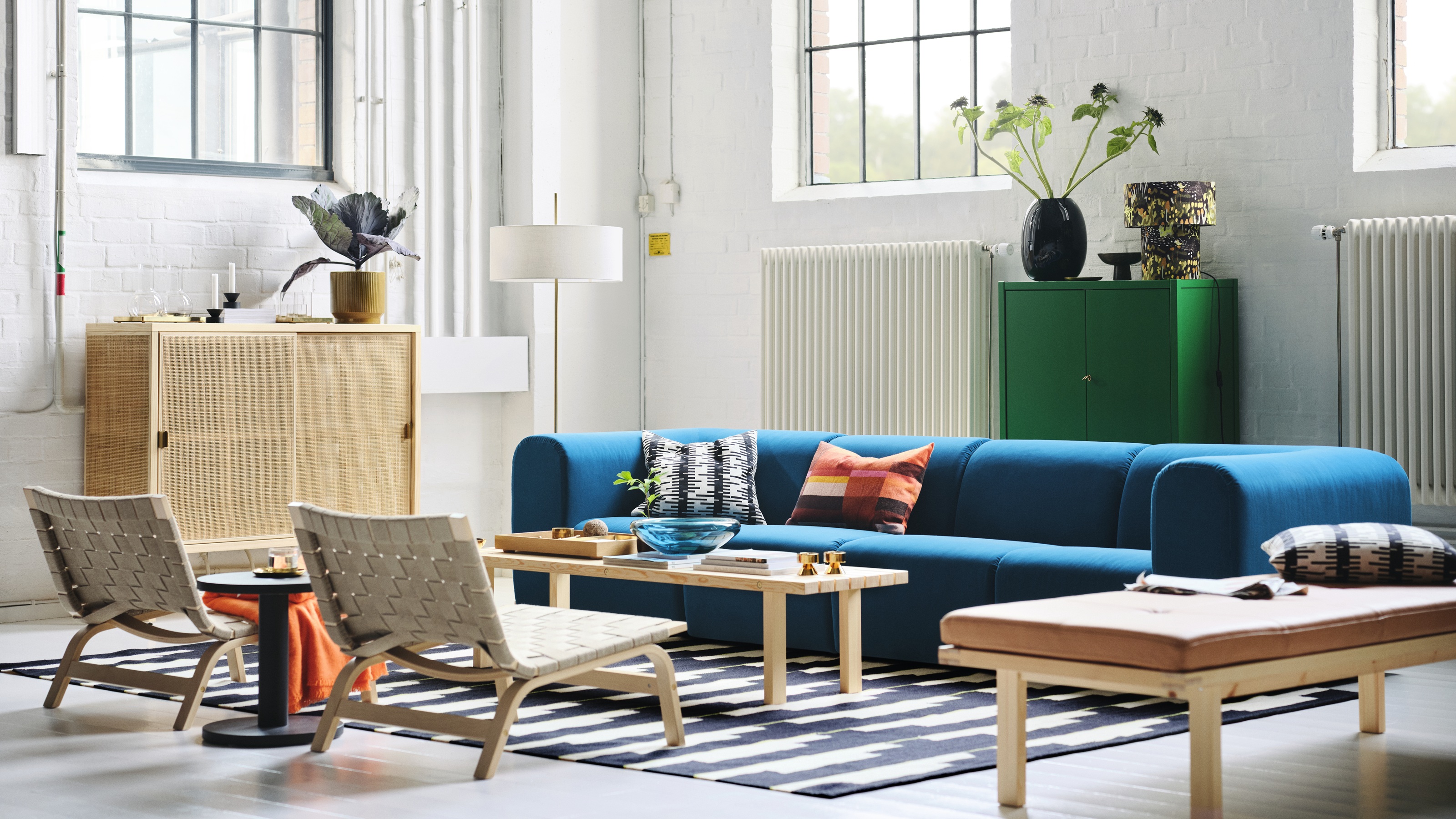 an ikea set with a large blue sofa and wooden furniture in a large white, light room