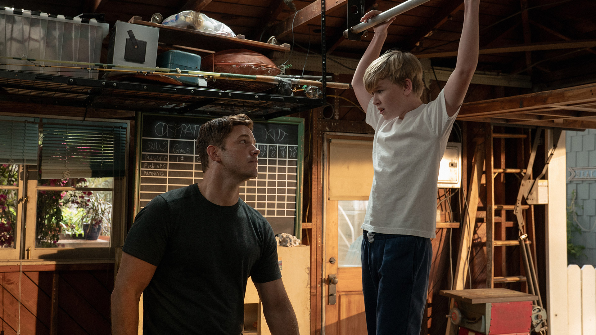 Chris Pratt looks at Jude Hill doing a pull up in Apple TV's Way of the Warrior Kid