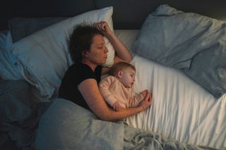 A woman and baby asleep in bed