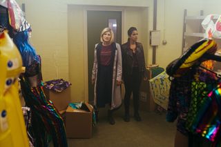The Doctor (Jodie Whittaker) and Yaz (Mandipp Gill) seem confused as they find themselves in a storage unit filled with brightly coloured clothing and objects