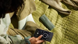 Sonos Roam on a blanket as someone controls it with their phone