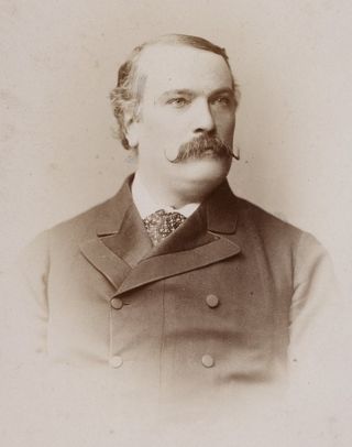 a black-and-white portrait of a man in a suit with a large mustache
