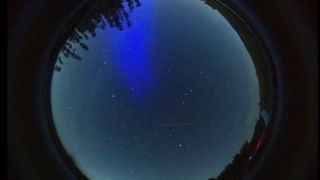 a 360 view of the night sky with a huge blue pillar reaching into the night sky.