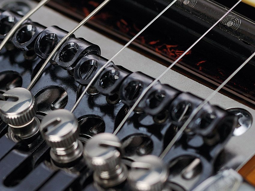 The mechanical gears on the bridge turn to tune the strings.
