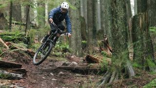 Remy Metailler doing a jump on a bike in a forest
