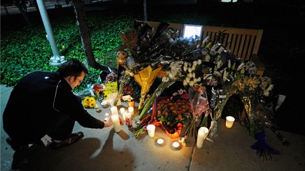 Flowers and Apple iPad showing a picture of Jobs are placed at a makeshift memorial