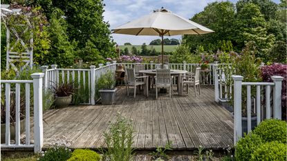  Sunny wooden decking area, L shaped sofa, colourful cushions, Moroccan Moorish style garden