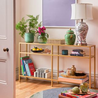 Gold finish shelving unit decorated with books, trinkets, and lamps in living room
