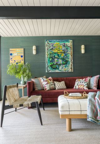 Seating area with red sofa and green walls with paintings on