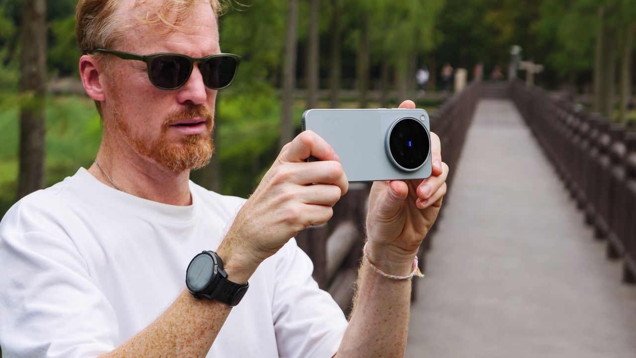 Tim Coleman, TechRadar's Cameras Editor, holding the Vivo X500 Pro Max phone while stood on a wooden walkway in a birdlife reserve in Shanghai, China