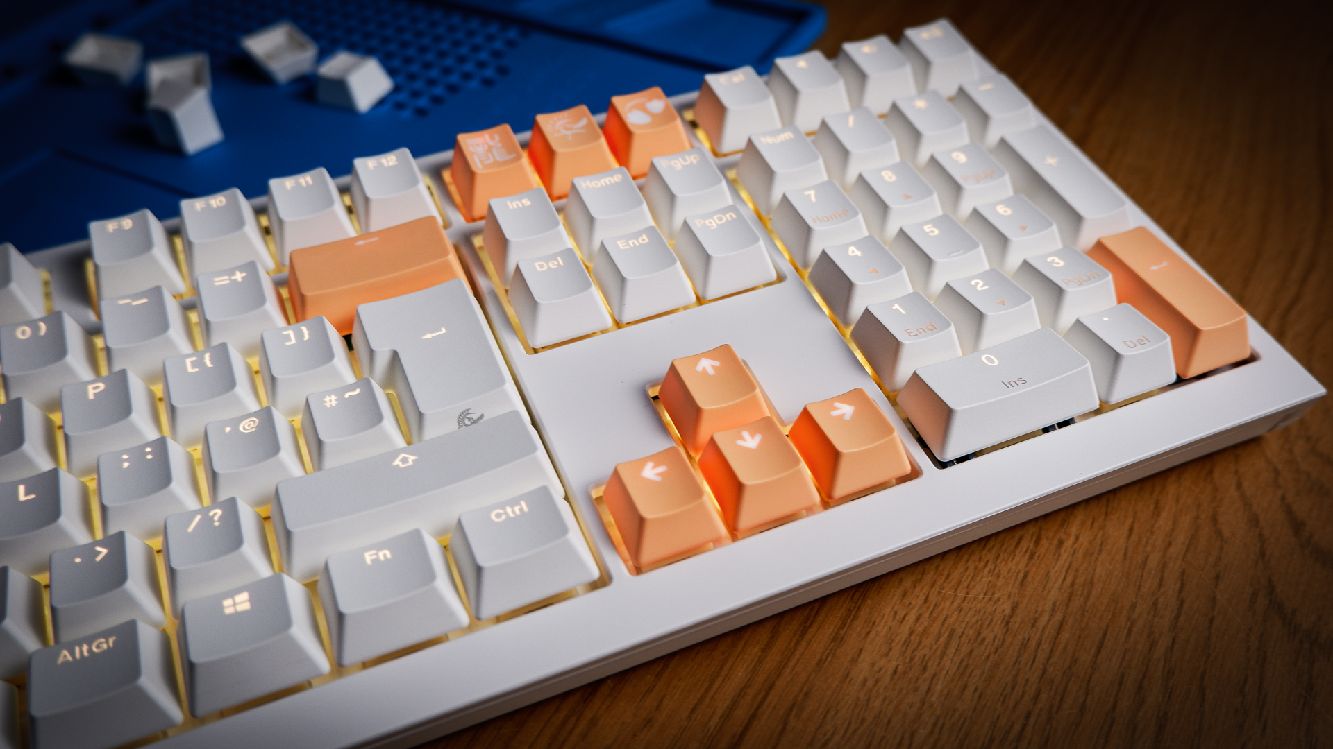 The Ducky One X induction gaming keyboard on a blue mat on a desk, with keycaps removed.