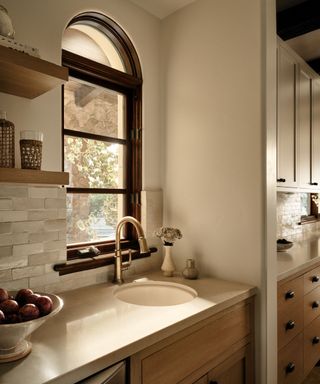 A corner of a transitional kitchen with curved, Spanish-style windows