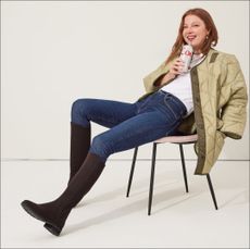 Woman wearing Rothy's the tall lug boot in truffle brown with jeans white t-shirt and quilted jacket