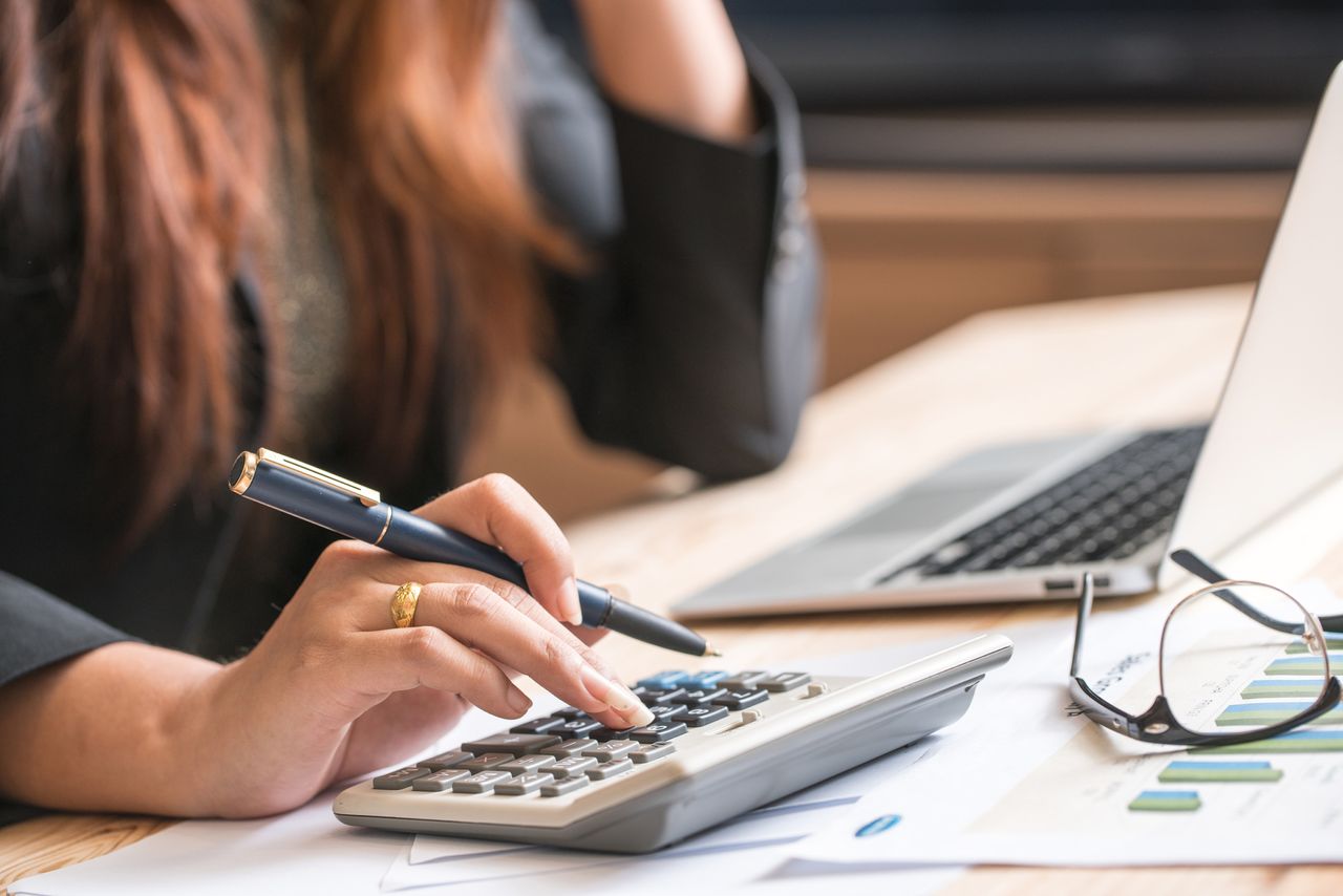 person looking at computer and calculator