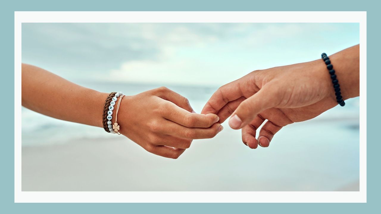 How often does your partner think about breaking up? Pictured: Couple&#039;s hands splitting apart with the beach in the background