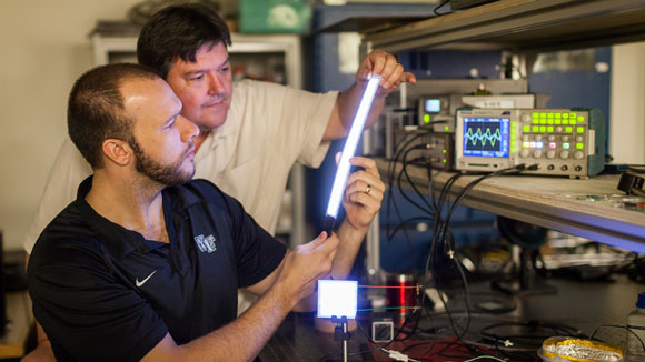 Wake Forest PhD student Greg Smith (left) and lead researcher David Carroll light up a FIPEL bulb