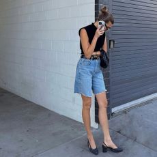 Woman on the phone wearing denim shorts, black top, and slingbacks