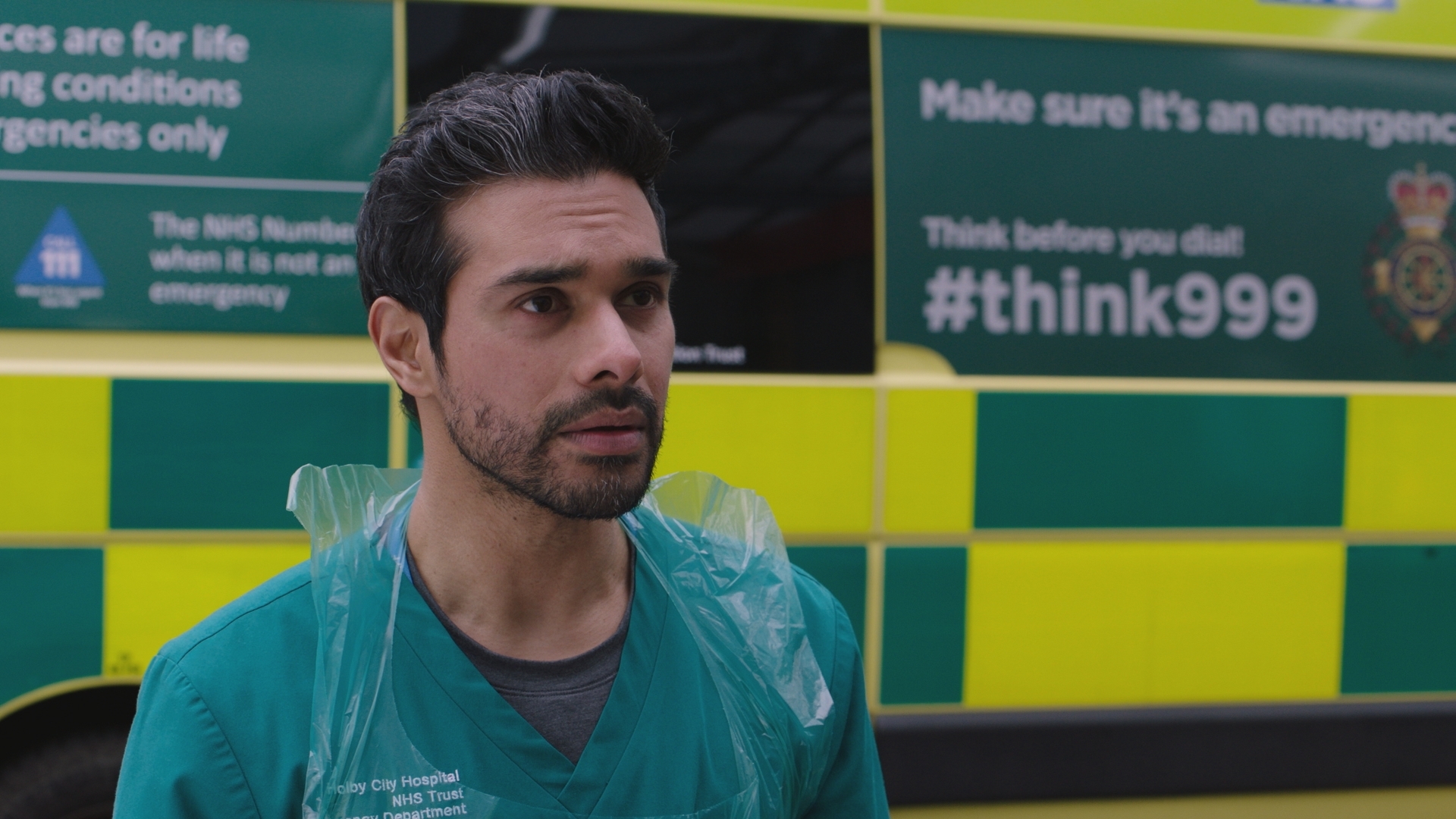 Rash stands outside Holby ED in front of an ambulance, wearing his green scrubs and a disposable plastic apron.