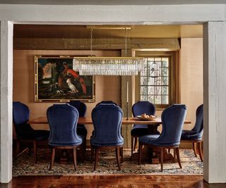 Luxury heritage dining room displayed between double doors, with royal blue upholstered chairs and persian rug underneath
