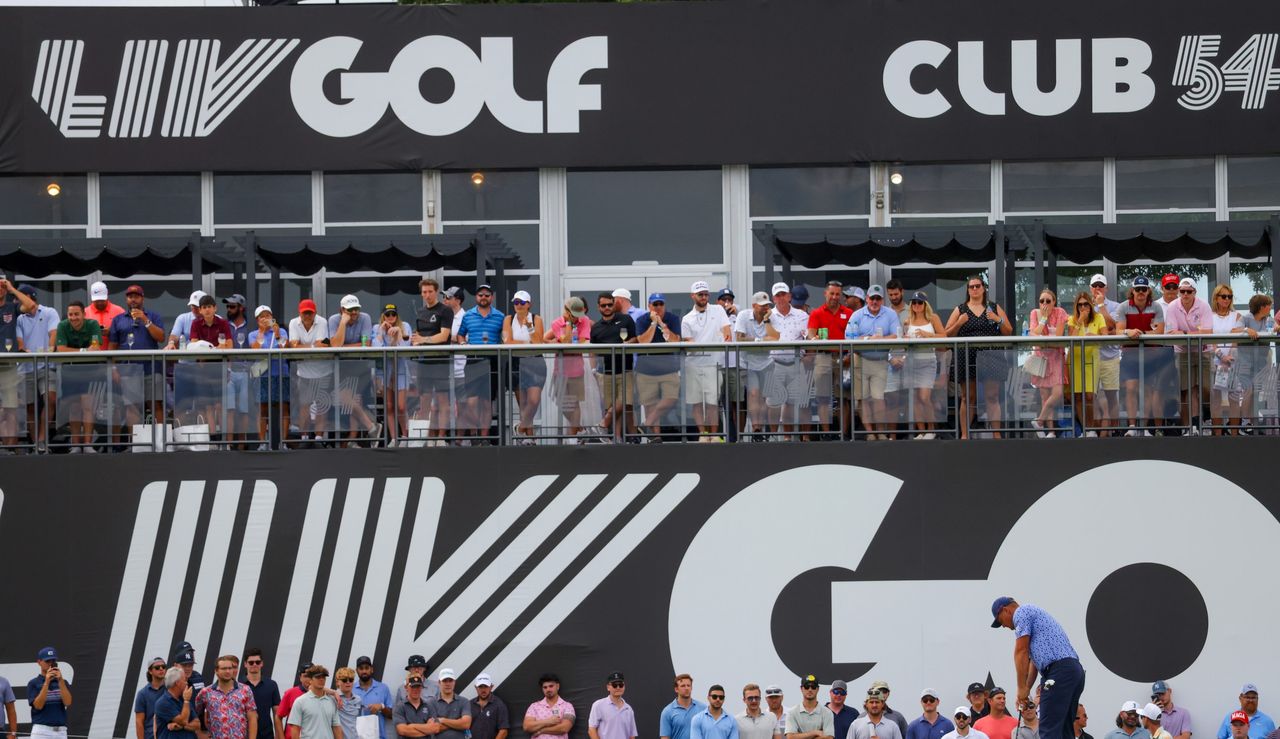 DeChambeau putts in front of a LIV Golf Banner