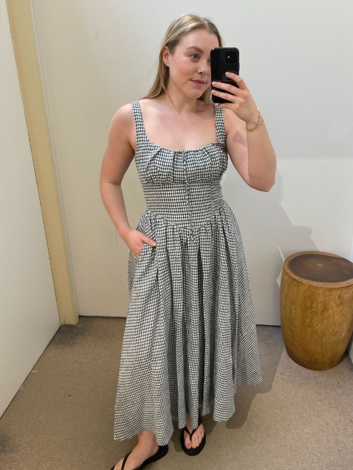 Woman wears gingham dress and black flip flops