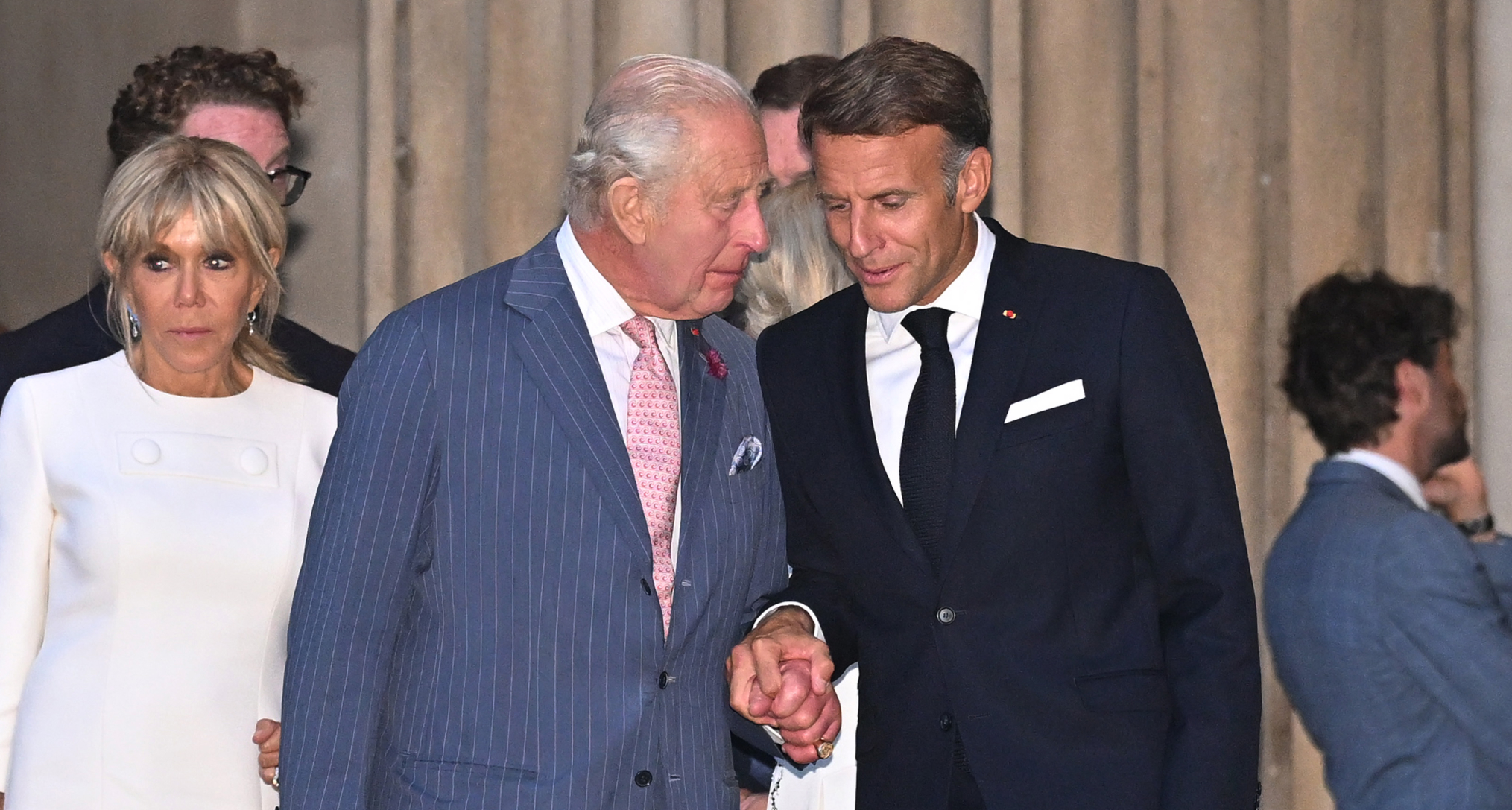 King Charles holding hands with Emmanuel Macron