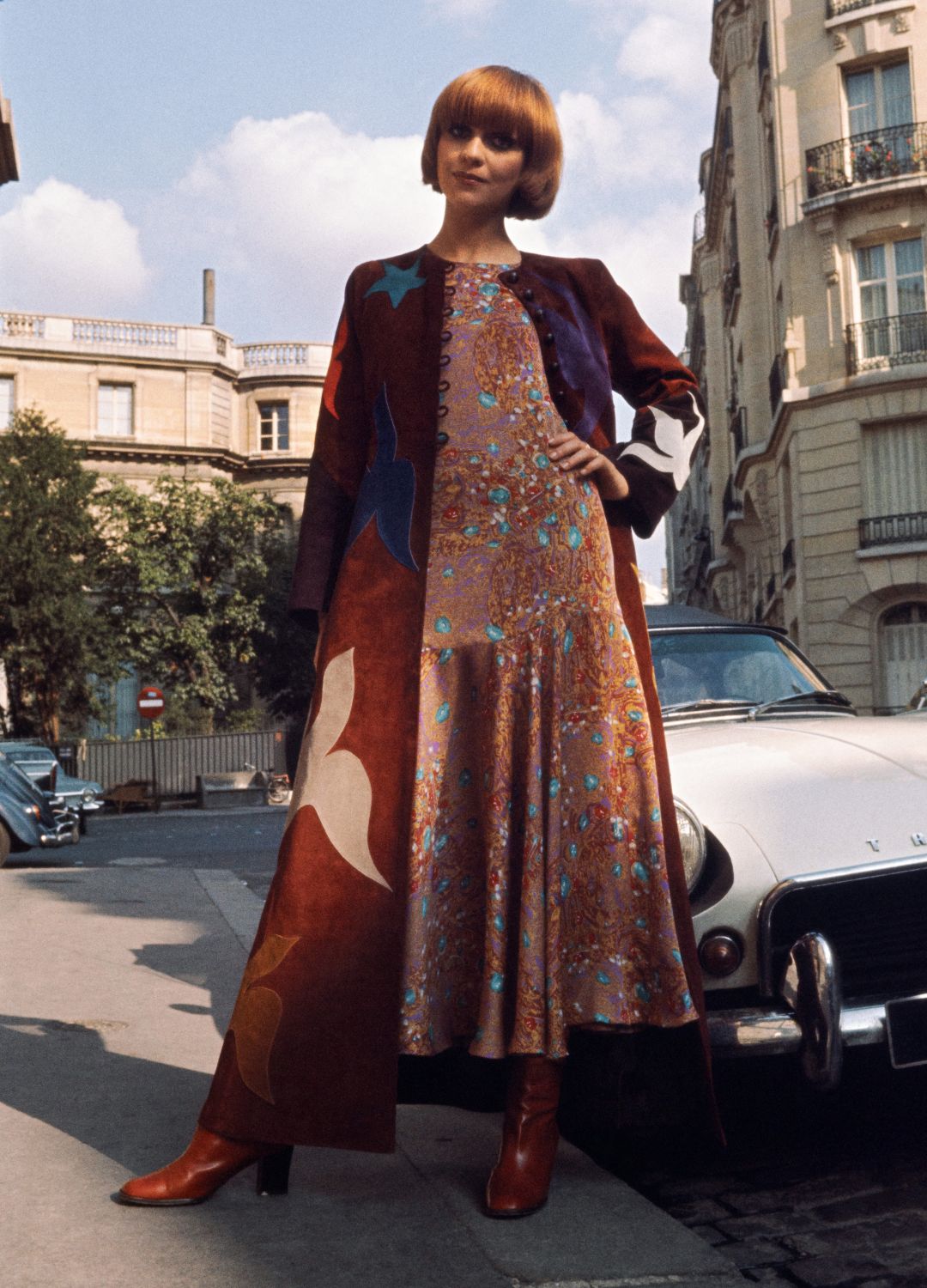 A model presents a creation composed of a long brown suede coat with multicolored birds and stars worn over a brown and blue crepe dress by Yves-Saint-Laurent for the Fall/Winter 1970-1971 collection in France 30, 1970, in Paris.