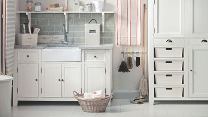 Cream utility room with a sink, cabinets, and a wicker basket on the floor