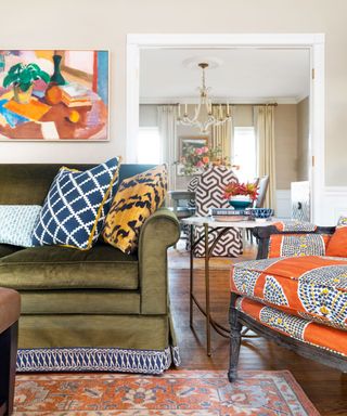 A maximalist living room with a green couch and a bright orange armchair