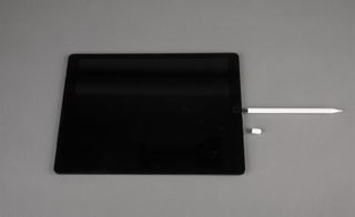 View of an Apple Pencil plugged into an iPad Pro pictured against a grey background