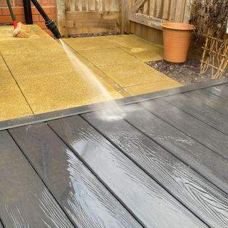 Grey decking being cleaned with power washer
