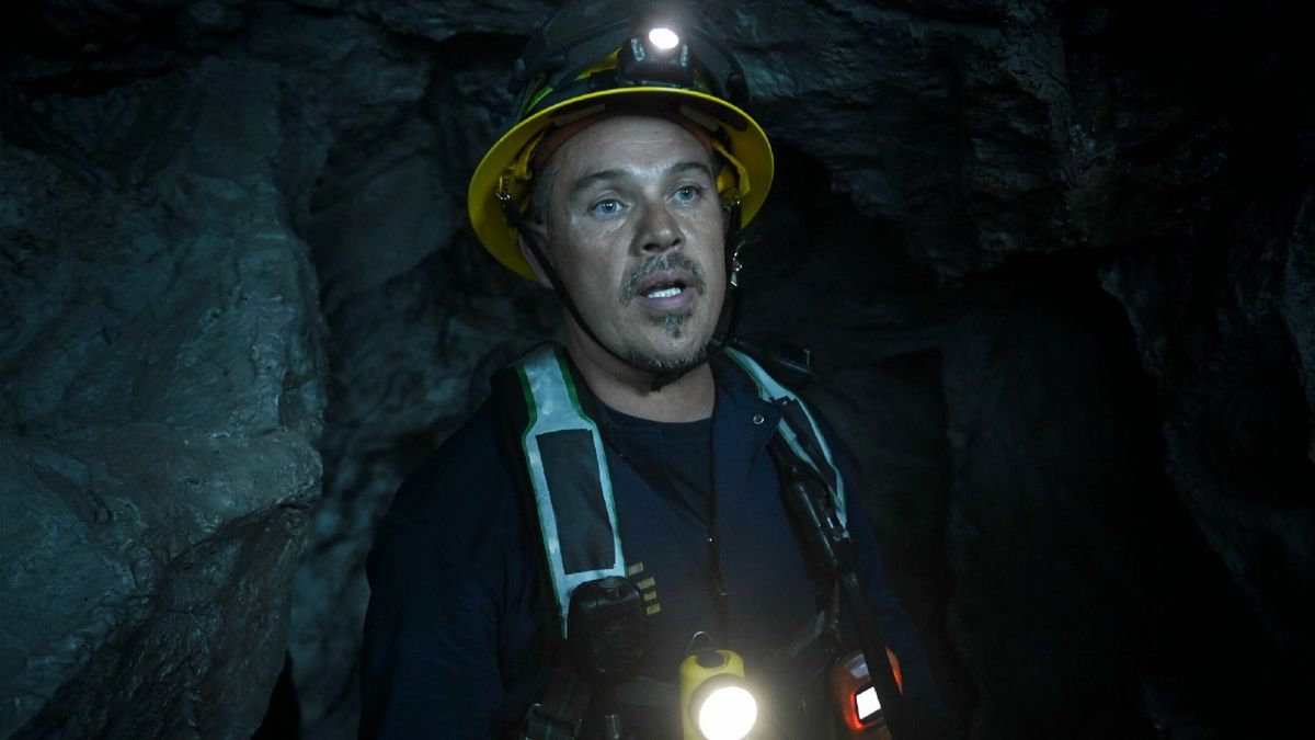 Pictured: Kevin Alejandro as Manny Perez in a cave wearing a hard hat and light.. 