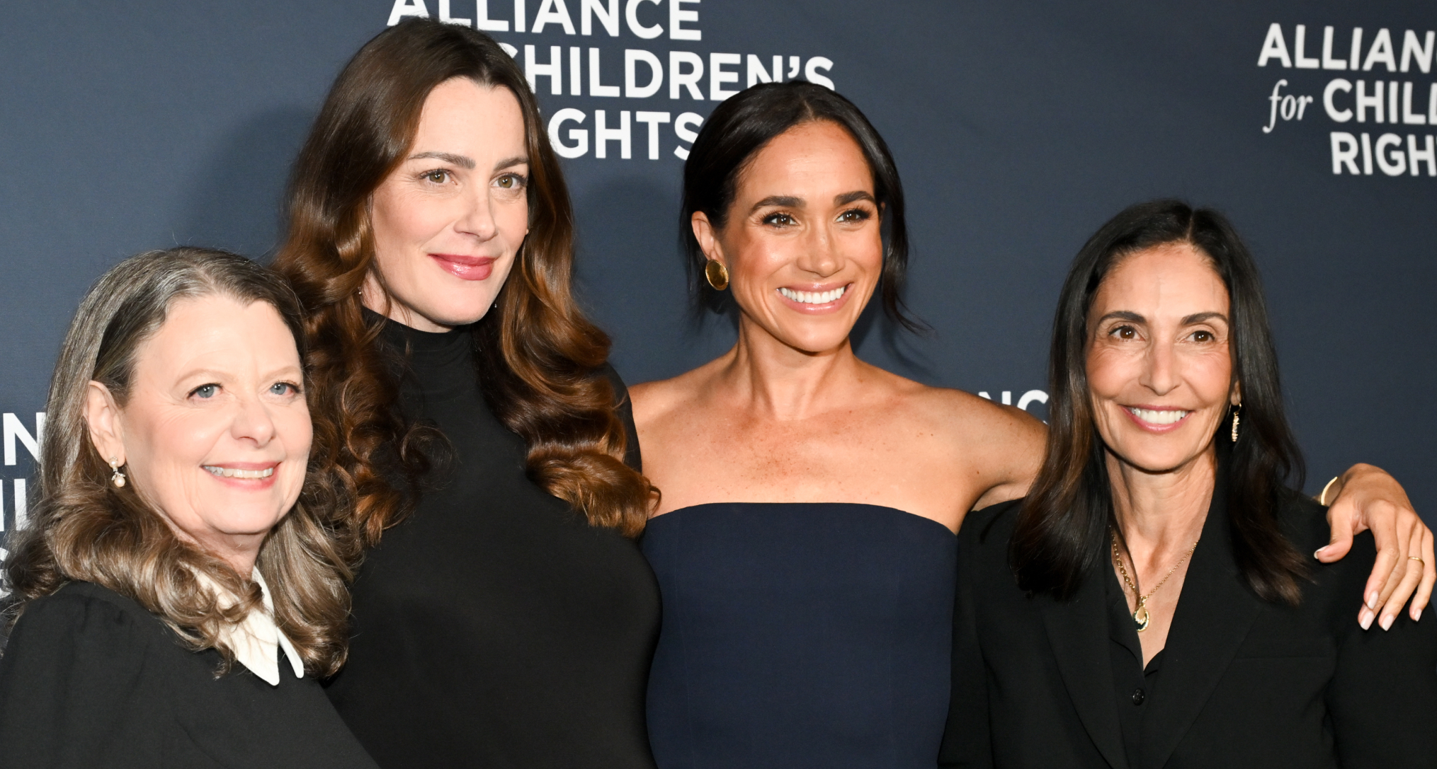 Meghan Markle posing with friends in a navy gown at the Alliance for Chilren's Rights event