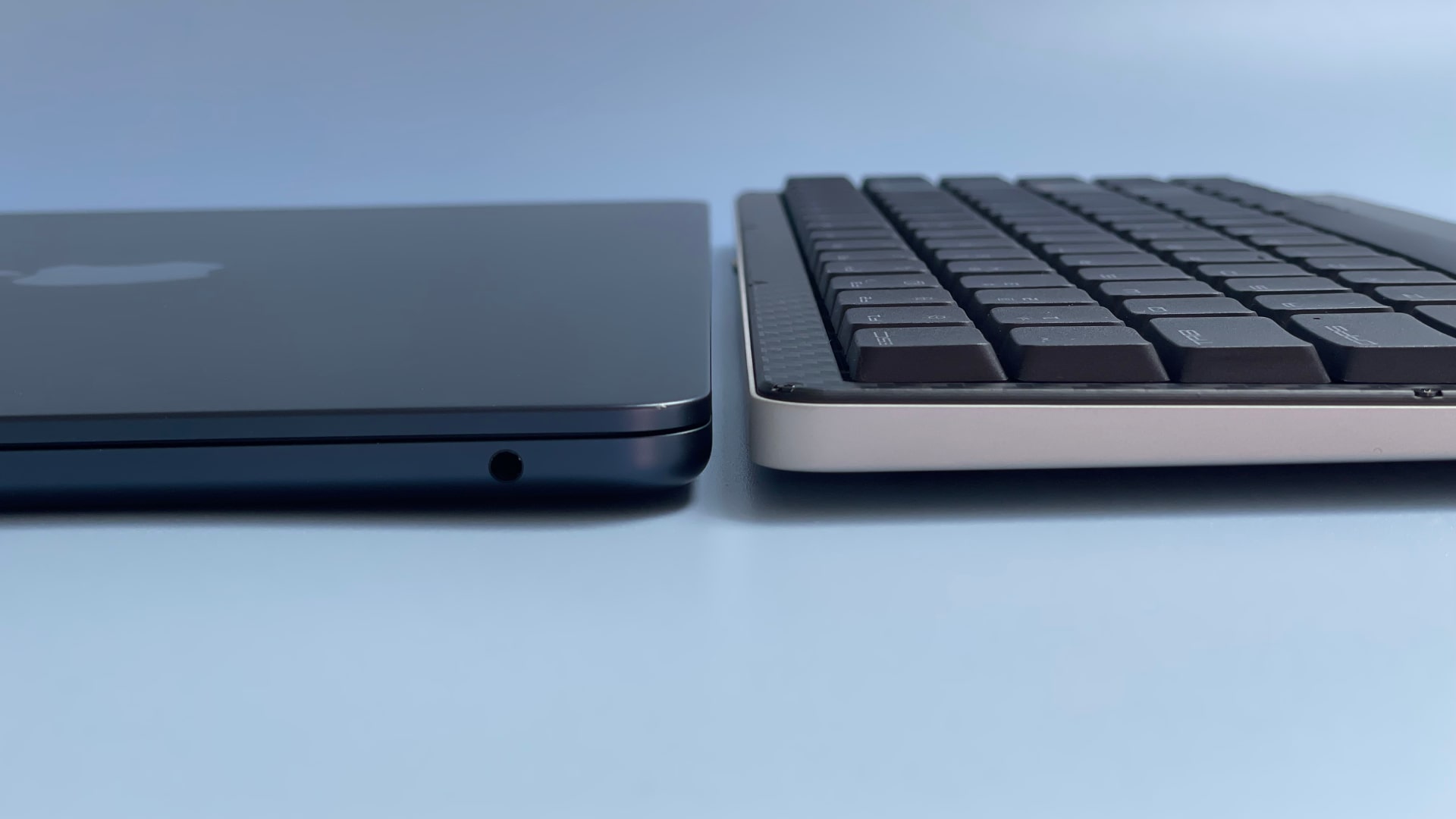 The Lofree Edge keyboard and MacBook Air laptop against a blue background.