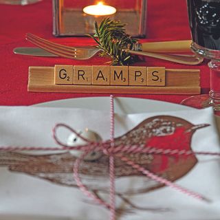 dining table with scrabble racks and tiles napkin knife fork and twine