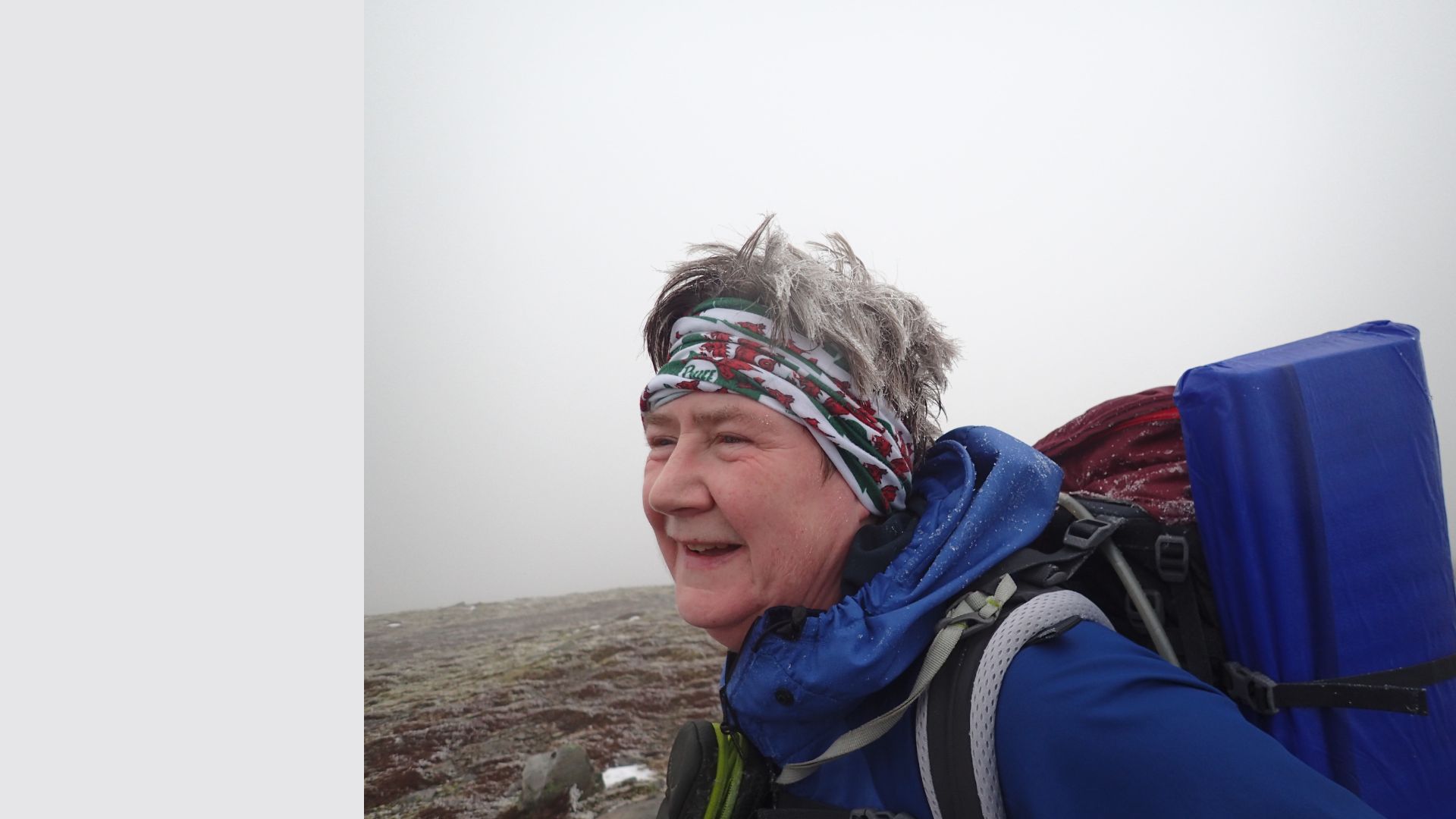 Kate Gilliver wearing hiking clothing and backpack standing on cloudy hilltop
