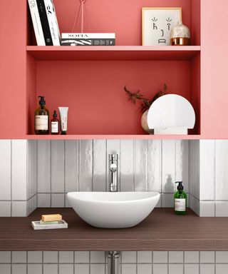 A bathroom with pink built-in shelving in an alcove above a white sink