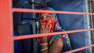 a migrant worker looks out of a compartments window as she sits inside a special train going to agra in uttar pradesh state during a government imposed nationwide lockdown as a preventive measure against the covid 19 coronavirus, at sabarmati railway station on the outskirts of ahmedabad on may 2, 2020 photo by sam panthaky afp photo by sam panthakyafp via getty images