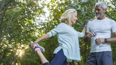 Woman holding her foot behind her with her knee bent, holding on to a man’s shoulder