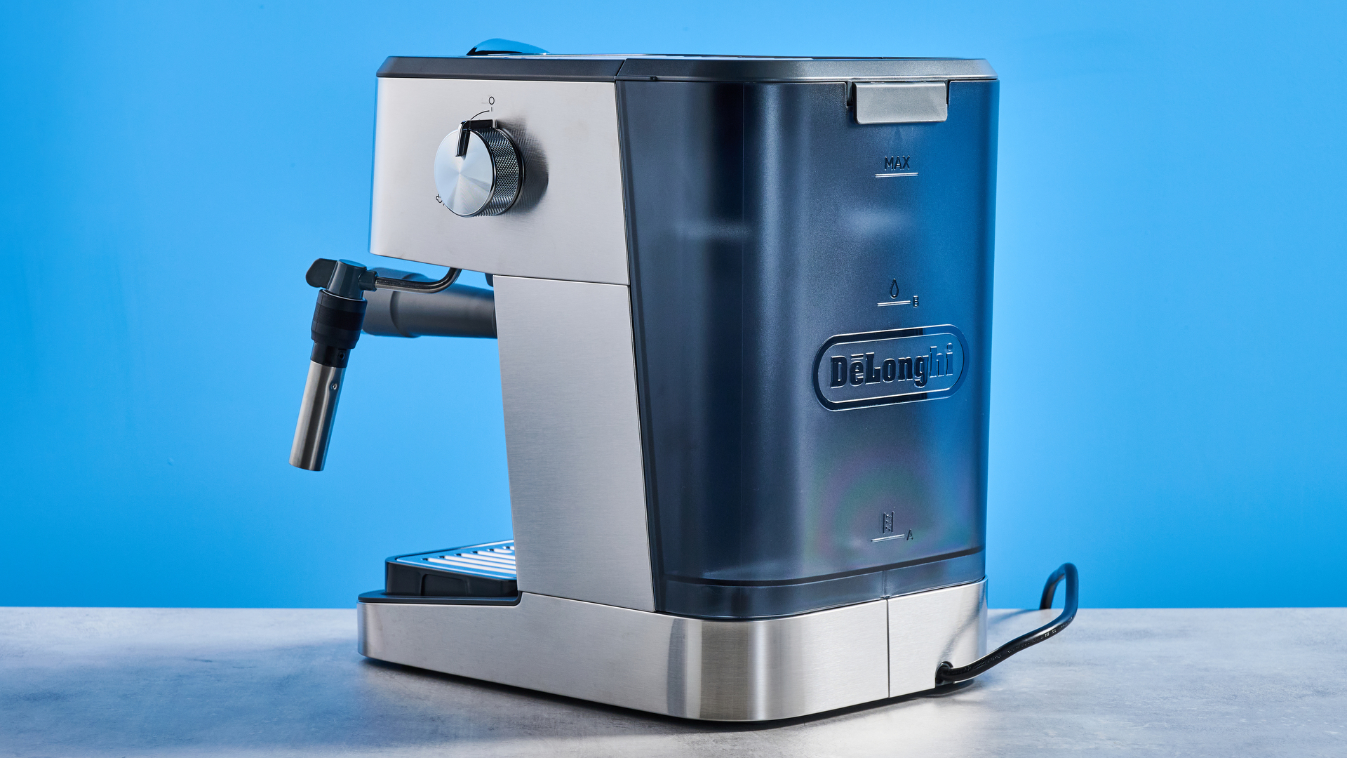 the De'Longhi Linea Classic espresso machine photographed against a blue tom's guide background, showing its silver finish, steam dial, steam wand, portafilter, and accessories