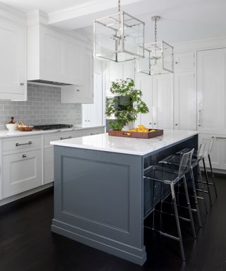 A kitchen with glossy white cabinetry and a blue grey, marble-topped island