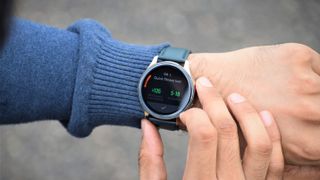 Bästa Android-smartklocka: En man bär en OnePlus Watch i Cobalt Limited Edition och håller på att kolla statistik på urtavlan utomhus.