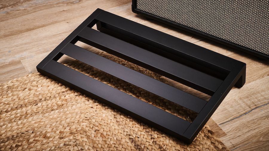 A Pedaltrain Classic 1 pedalboard on a wooden floor with a guitar amplifier